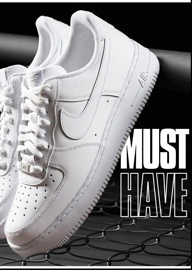 Paire de sneakers Nike Air Force 1 blanches posée en suspension sur un grillage noir, avec le texte 'Must Have' en blanc.